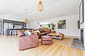 Open living area with leather sofa and fireplace, in the background dining area and fitted kitchen