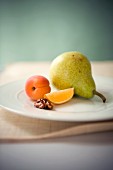 An arrangement featuring a pear, an apricot, an orange wedge and half a walnut