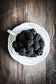 Fresh blackberries in a teacup on a wooden table