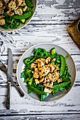 Grilled chicken with spinach, rocket and peas on rustic wooden surface