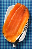 Two slices of smoked salmon on a plate (seen above)