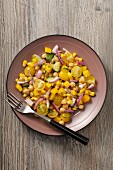 A yellow vegetable salad with tomatoes, sweetcorn, peppers and chickpeas
