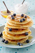 A stack of pancakes with honey and blueberries