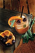 Apple and bourbon cocktail with oranges and cherries