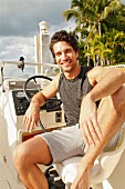 A young man sitting at the wheel of a motor boat