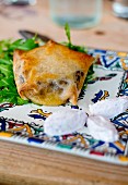 Pastilla filled with dark and pine nuts on an Arabic plate with goat's cheese and salad (Morocco)