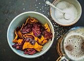 Colourful vegetable crisps (carrots, parsnips and beetroot) with salt and a beer