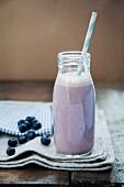 A blueberry and banana smoothie in a bottle with a straw