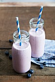 Two bottles of blueberry and banana smoothie with straws
