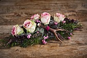 Alpine-style arrangement of roses, antlers, snowberries and heather