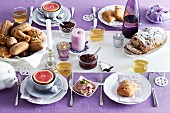 A table laid for breakfast with a purple tablecloth and white plates