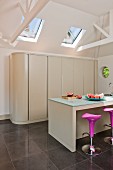 Modern kitchen with island counter, bar stools and kitchen counter behind sliding doors