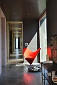 Classic red easy chair next to panoramic window in room painted dark grey