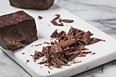 Schokoladenstücke und geraspelte dunkle Schokolade auf Marmoruntergrund