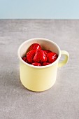 Thawed strawberries in an enamel mug