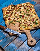 Tarte flambée with bacon and onions on a chopping board