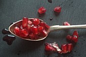A spoonful of pomegranate seeds on a slate surface