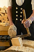 Ein Handwerker bearbeitet ein Stück Holz mit einem Schindelmesser
