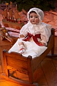 Historisches Weihnachtsspielzeug: Antike Puppe mit Schlafhaube in einem Puppenbettchen