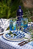 Sommerlich gedeckter Tisch mit blau-weißem Geschirr und Zweigen