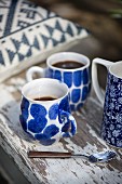 Two blue-patterned coffee cups on weathered wooden board