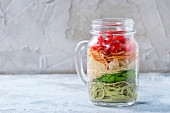 Colourful spaghetti with tomatoes, basil and cheese in a glass