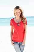 Junge Frau in rotem Shirt und Jeans am Strand