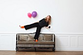 A young woman standing on one leg on an old sofa