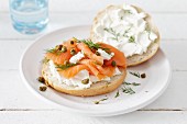 A bread roll topped with smoked salmon, goat's cream cheese and capers