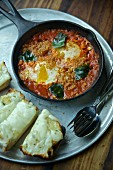 Eggs with tomatoes and basil in a pan served with cheese on toast