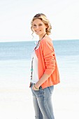 Junge Frau in Top, Strickjacke und Jeans am Strand