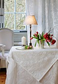 White damask tablecloth, table lamp and vase of tulips on table