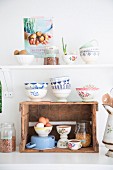 Vintage-style bowls on kitchen shelf and wooden crate