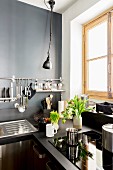Dunkle Küche mit grauer Wand und Wandhalterung für Utensilien