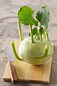 A kohlrabi with leaves on a wooden board