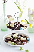 Pieces of chocolate and foil-wrapped Easter eggs on a cake stand