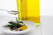 Olivenöl in eine Schüssel mit schwarzen Oliven gießen
