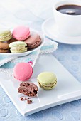 Macaroons on a white tray on a light blue surface with a cup of coffee in the background