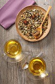 Herb tea with spices: loose leaf tea on a plate and brewed in glass cups