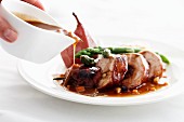 Gravy being poured over sliced pork roulade