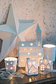 Village of illuminated, ceramic, house-shaped tealight holders in front of large white star