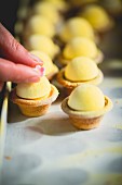 Lemon tartlets being decorated with sugar flowers