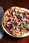 Pizza with ham, rocket and tomatoes