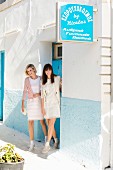 Zwei Frauen in weißen Sommerkleidern vor einem Haus
