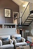 Armchairs in traditional interior with steel staircase in background