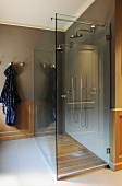 Double shower with modern glass screen and wooden floor in bathroom with traditional wainscoting and tiled floor