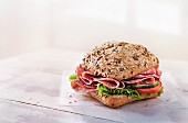 A wholemeal roll with salami, vegetables and lettuce