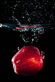 A red apple falling in water with a splash