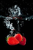 Strawberries falling in water with a splash