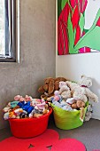 Bunte Plastikwannen mit Plüschtieren in Kinderzimmerecke mit Betonwand und modernem Bild